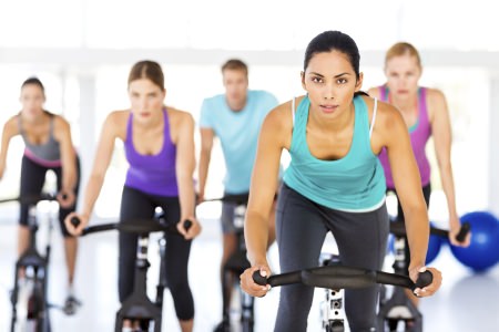 Fitness Class Spinning On Bikes In Gym